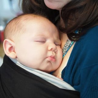 baby sleeping in baby wrap on mother's chest