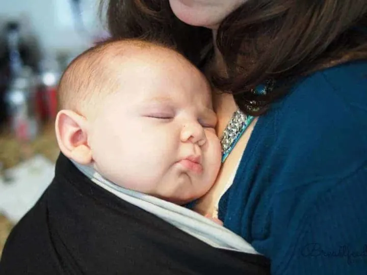 baby sleeping in baby wrap on mother's chest